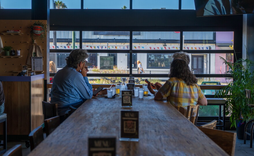 Carol Kuck and her friends sit at a large table at One of Us in North Park on July 22, 2026.