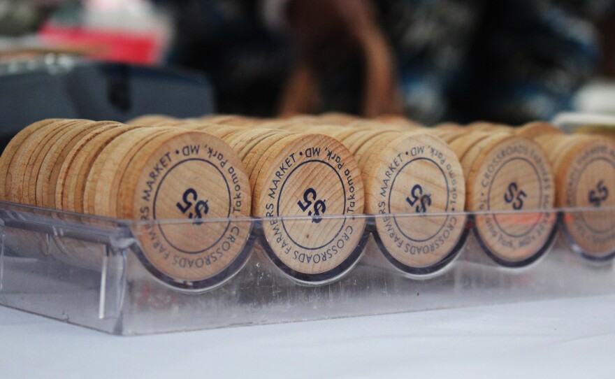 These wooden tokens are handed out to shoppers who use SNAP benefits to purchase fresh produce at the Crossroads Farmers Market near Takoma Park, Md. Customers receive tokens worth twice the amount of money withdrawn from their SNAP benefits card — in other words, they get "double bucks."