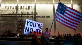 Protestors wave a U.S. and signs as workers prepare to remove President Donald Trump's name from the John F. Kennedy Center for the Performing Arts in Washington, Saturday, June 13, 2026.