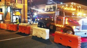 A worker fills barriers with water on one of the cross streets along the route of the Rose Parade on Sunday evening, Jan. 1, 2017, in Pasadena, Calif. 