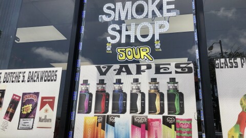 A sign advertising vapes and cigarillos hangs in the window of Fuego Smoke Shop, May 18, 2022.