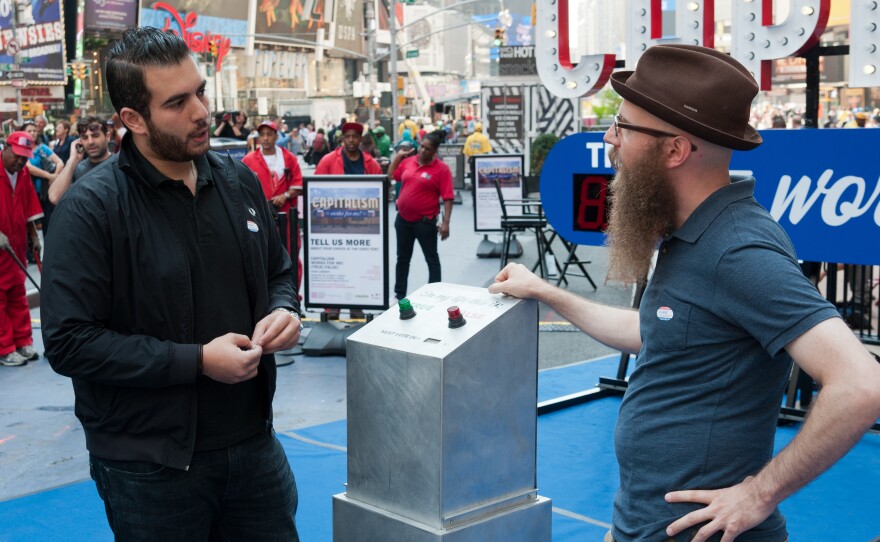 Artist Steve Lambert, right, asks people to vote on whether capitalism is working — for them. The art installation is in Times Square through Oct. 9.