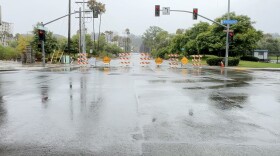 Signs warning of flooding and street closures at a flooded intersection of Riverwalk Drive in Mission Valley, Aug. 20, 2023. 