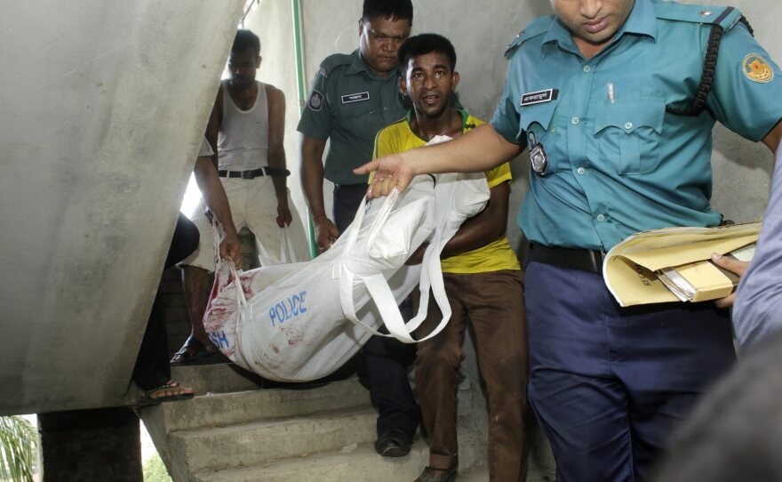 Police and others carry the body of activist and blogger Niloy Chakrabati, aka Niloy Neel, downstairs after he was slain in his upstairs apartment.