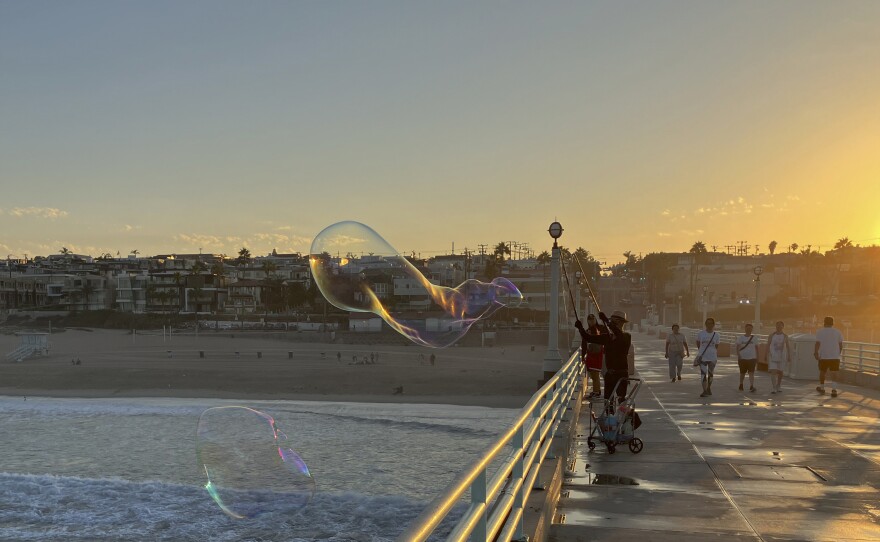 A man creates giant soap suds bubbles at dawn Monday, Sept. 5, on the Manhattan Beach Pier in Manhattan Beach, Calif., as a severe heat wave gripped the state. Most of California's 39 million people are facing sweltering weather.