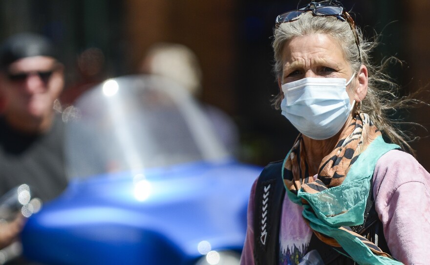 DEADWOOD, SD - AUGUST 08: A woman crosses the street as motorcyclists ride through Deadwood, South Dakota during the 80th Annual Sturgis Motorcycle Rally. Despite the pandemic this years rally drew nearly half a million attendees.   (Photo by Michael Ciaglo/Getty Images)
