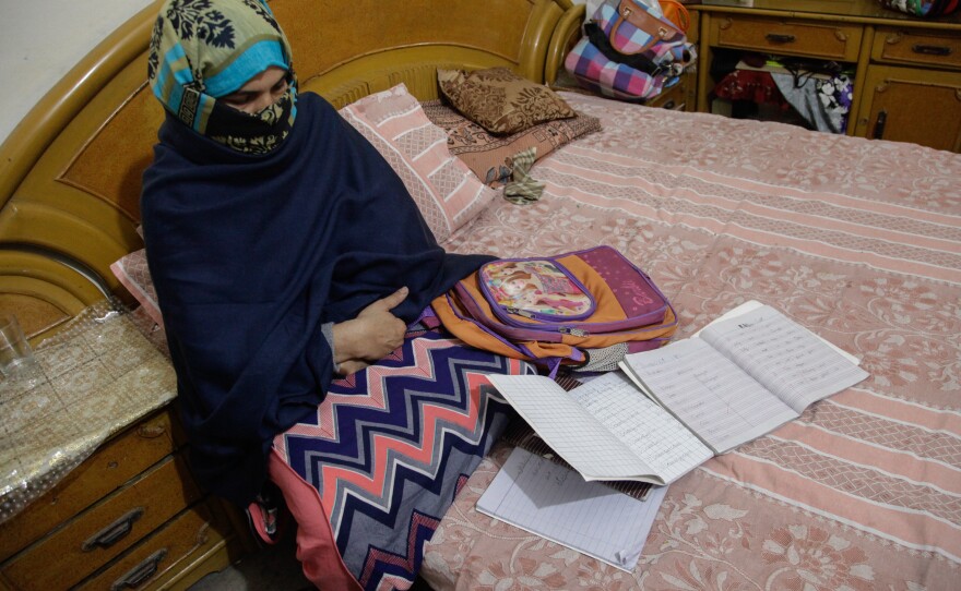 Zainab's mother, Nusrat Amin, sits with her slain daughter's school bag and notebooks.