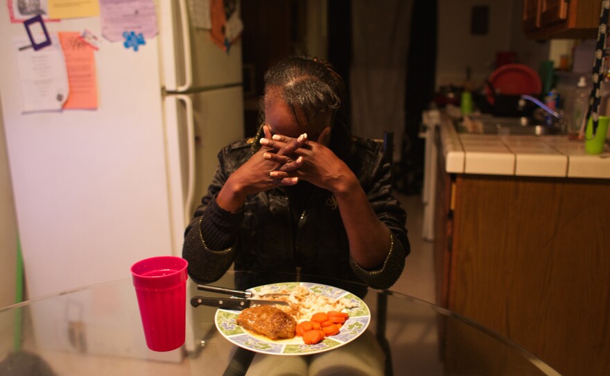 Erica Johnson prays before her meal. She volunteers at the food pantry at John Still school where three of her four children are students. She eats alone after she feeds her kids.