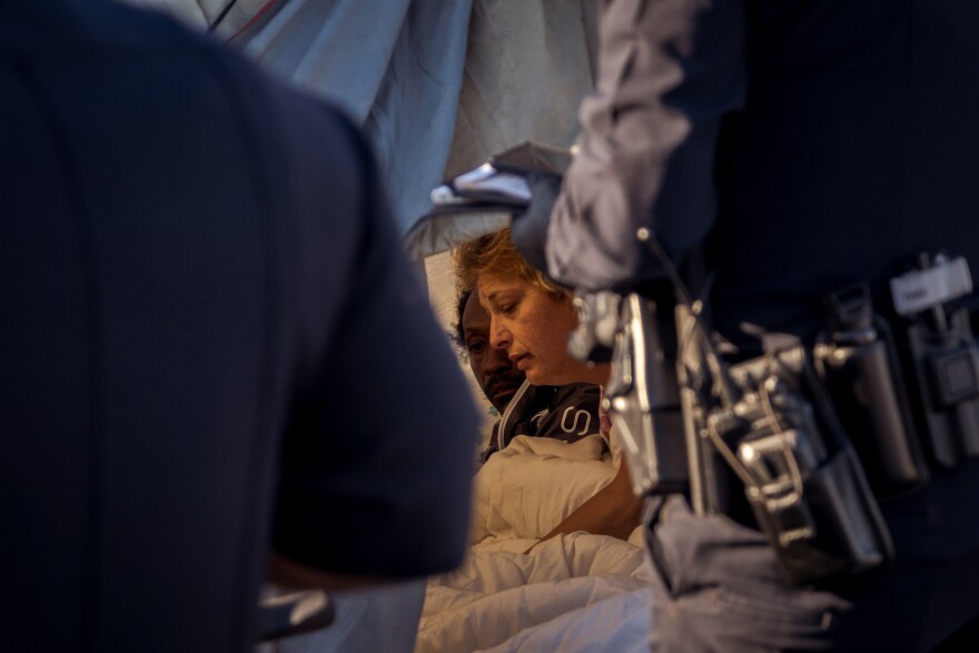 A couple living in a tent at a homeless encampment on Sports Arena Boulevard in San Diego's Midway District is awoken by San Diego Police Officers beginning their enforcement of the City of San Diego's anti-encroachment and illegal lodging laws, February 14, 2022.