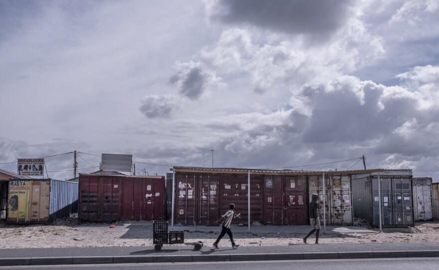 Boys walk past shuttered businesses in the township of Khayelitsha in Cape Town, South Africa, during the coronavirus lockdown. This recession is the first triggered solely by a pandemic, and low-income countries are particularly hard-hit.