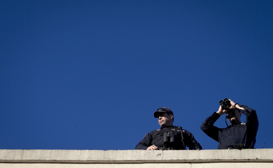 Police snipers stand on a roof as they monitor the area for Ramos' wake.