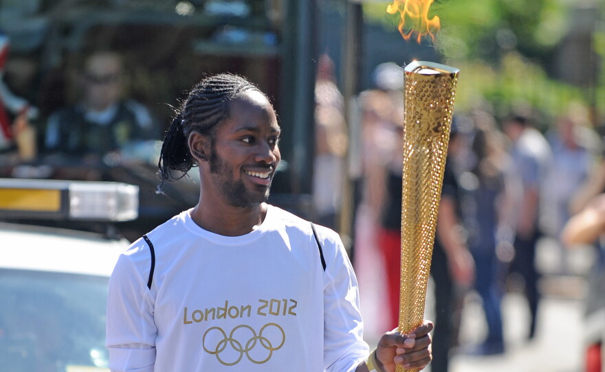 FILE — Torchbearer Jason Arday carries the Olympic Flame on the Torch Relay leg between Sutton and Merton, in London, July 23, 2012.