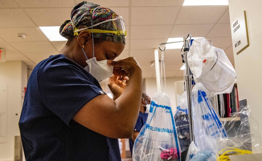 A medical worker puts on a mask before entering a negative pressure room with a Covid-19 patient in the ICU ward at UMass Memorial Medical Center in Worcester, Mass. on January 4, 2022.