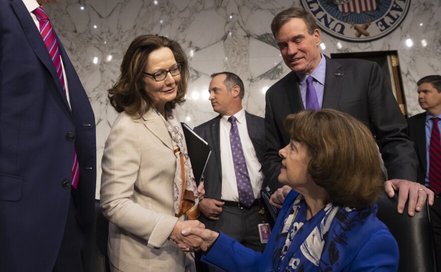 Gina Haspel (in white), the nominee to lead the CIA, is welcomed at her confirmation hearing before the Senate intelligence committee by Sen. Dianne Feinstein, D-Calif. (seated), and Vice Chairman Mark Warner, D-Va., in Washington on May 9. The committee voted 10-5 on Wednesday to recommend Haspel's confirmation by the full Senate.