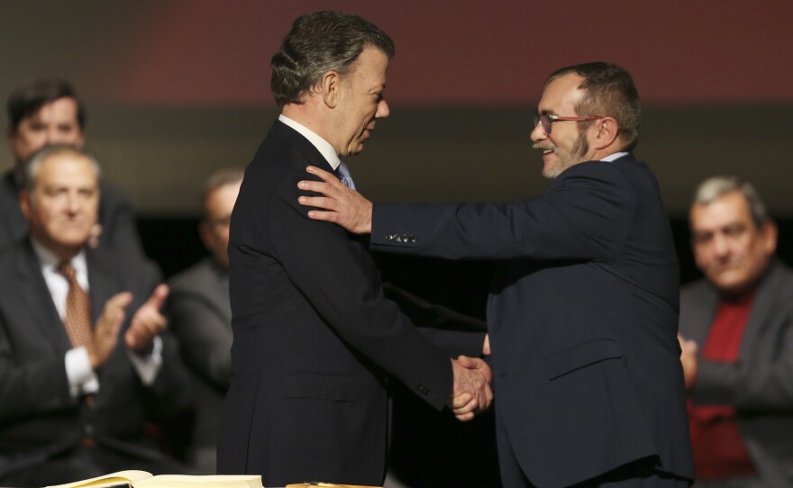 Colombia's President Juan Manuel Santos (left) shakes hands with with FARC leader Rodrigo Londono, known as Timochenko, after signing a revised peace pact in Bogota, Colombia, on Thursday.