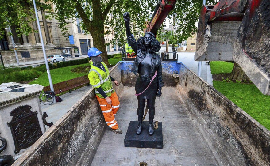 Contractors on Thursday remove Marc Quinn's statue, A Surge of Power (Jen Reid) 2020, after its temporary stint atop the plinth dedicated to slave trader Edward Colston in Bristol. Officials in the British city said the sculpture had been set up without their permission.
