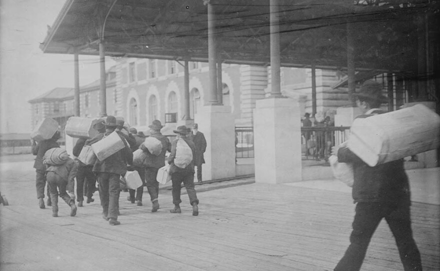Immigrants carrying luggage, Ellis Island, New York