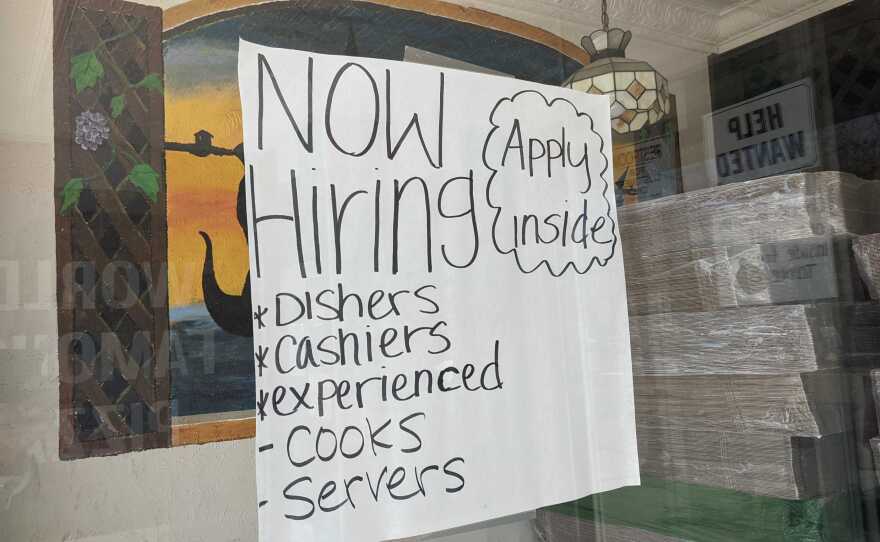 A "now hiring" sign hangs in the window of Filipe's Pizza in Escondido, Calif. Aug. 9, 2021.