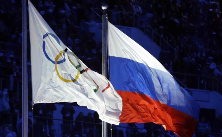 The Russian and the Olympic flags wave during the opening ceremony of the 2014 Winter Olympics in Sochi, Russia.