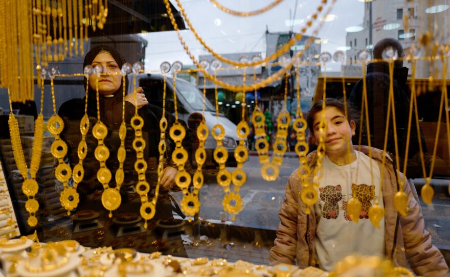 People in Ramallah look into the window of a gold store, one of the West Bank businesses affected by the economic decline resulting from Israel's war in Gaza.
