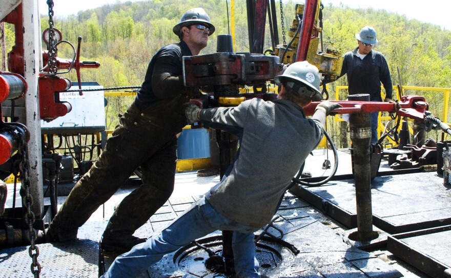 Workers move equipment at a natural gas well site near Burlington, Pa., in 2010. A federal report said Thursday natural gas production is on track to make the U.S. a net exporter of energy by about 2030.