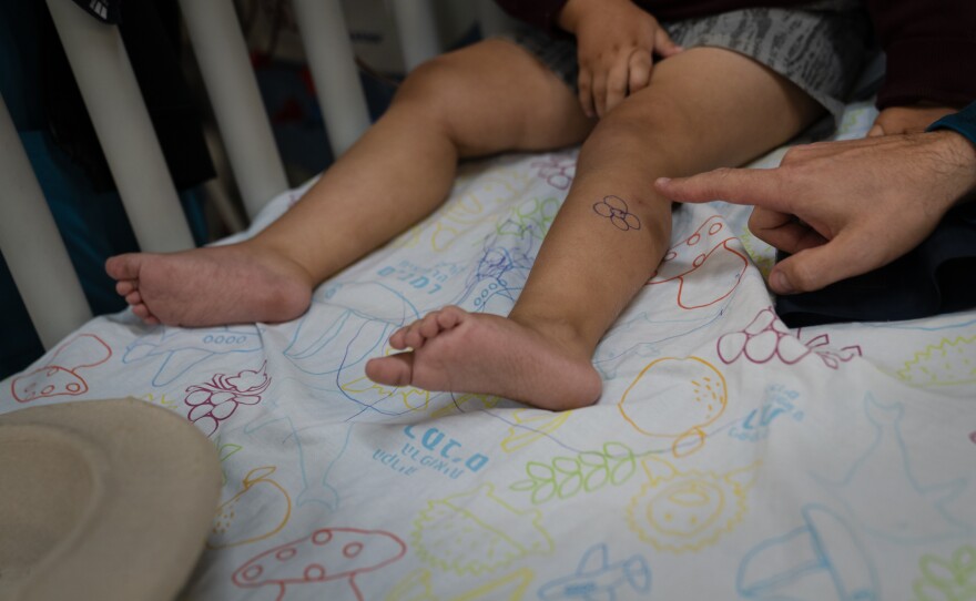 Tal Romano sits with his 4-year-old son, Hadar, who is receiving dialysis in the underground hospital in Haifa. A nurse drew a flower on Hadar's leg to make him laugh.