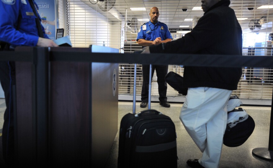 A TSA employee being trained in behavioral pattern recognition watches passengers in line at Boston's Logan International Airport in 2010. This week, Logan will become the first U.S. airport to require every passenger to go through behavioral profiling.