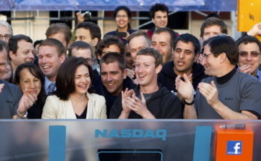 Mark Zuckerberg, chief executive officer of Facebook Inc., center, Sheryl Sandberg, chief operating officer of Facebook, center left, and Robert Greifeld, chief executive officer of Nasdaq OMX Group Inc., center right, applaud after remotely ring the opening bell for trading at the Nasdaq MarketSite from the Facebook campus in Menlo Park, California, U.S., on Friday, May 18, 2012.