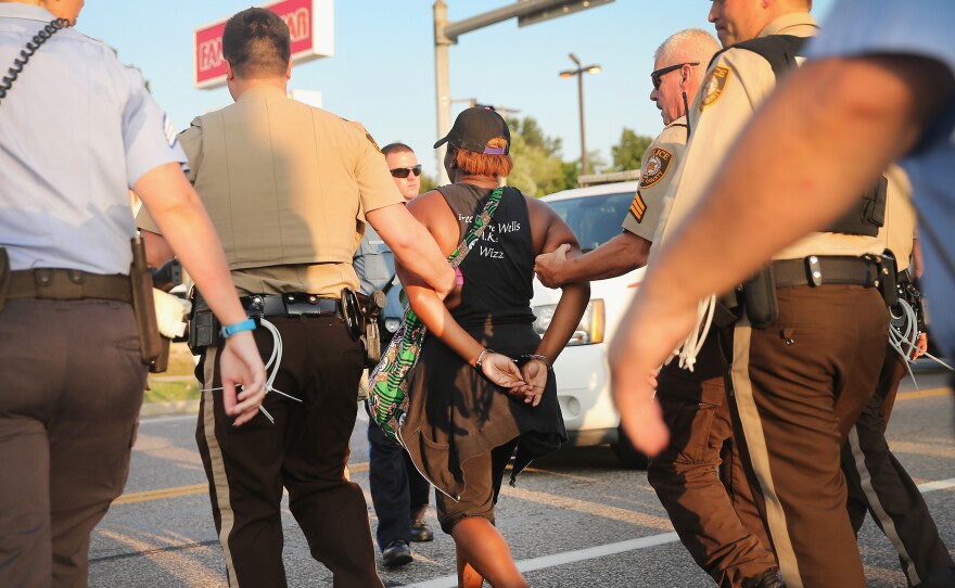 Police arrest a woman in Ferguson, Mo., protesting the shooting death of Michael Brown. Most officers in Ferguson and nearby Jennings are white, but the neighborhoods they police are predominantly African-American.