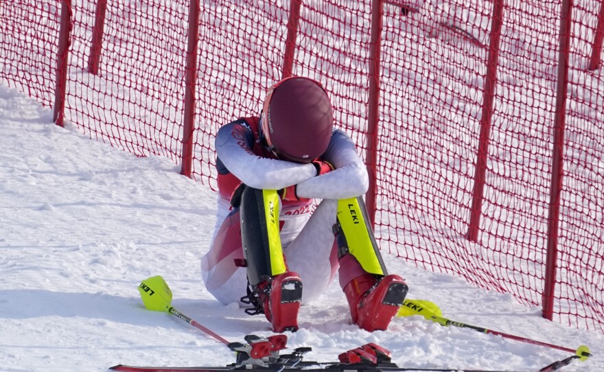 Shiffrin sits on the side of the course after skiing out in the first run of the women's slalom at the 2022 Winter Olympics.