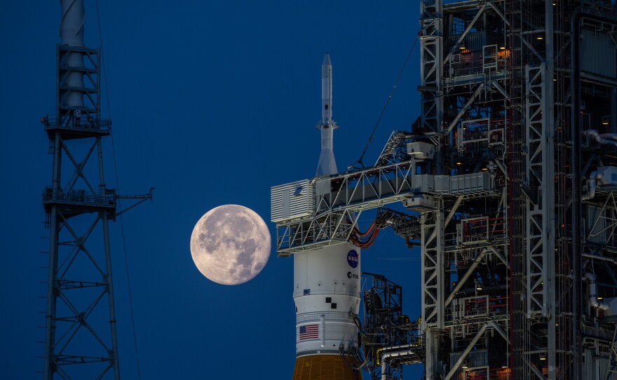 A full Moon is in view from Launch Complex 39B at NASA’s Kennedy Space Center in Florida on June 14, 2022. The Artemis I Space Launch System (SLS) and Orion spacecraft, atop the mobile launcher, are being prepared for a wet dress rehearsal to practice timelines and procedures for launch. The first in an increasingly complex series of missions, Artemis I will test SLS and Orion as an integrated system prior to crewed flights to the Moon. Through Artemis, NASA will land the first woman and first person of color on the lunar surface, paving the way for a long-term lunar presence and using the Moon as a steppingstone on the way to Mars.