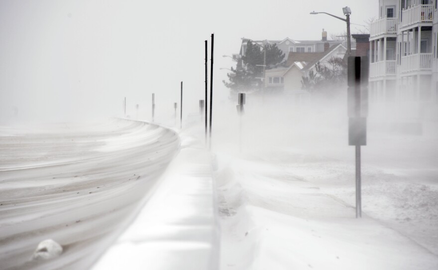 Winds whip snow from the beach across Winthrop Shore Drive in Winthrop, Mass.