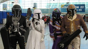 A group of Comic-Con attendees dressed as mariachi-inspired storm troopers stand under a Comic-Con banner on July 26, 2025.