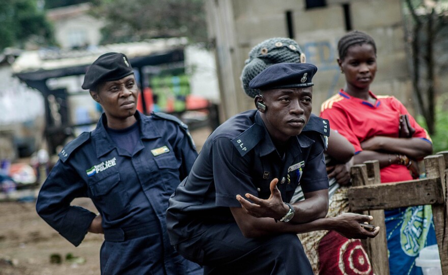 Police officers stand by as people visit the quarantined family on Sunday.