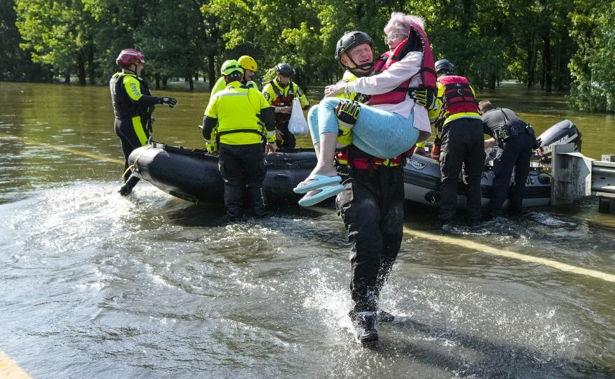 Conroe firefighter Cody Leroy carries a resident evacuated in a boat by the CFD Rapid Intervention Team from her flooded home in the aftermath of a severe storm on Thursday in Conroe, Texas.