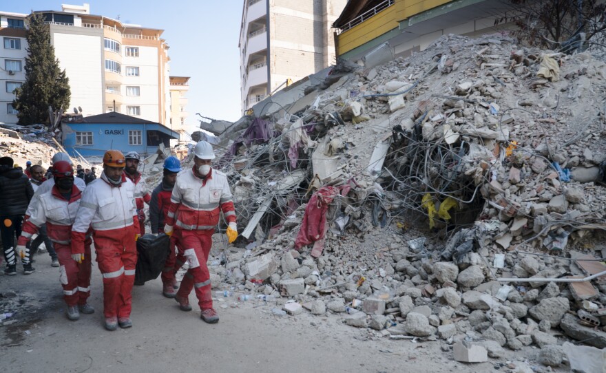 Workers transport a body out of the rubble of a building that collapsed in Islahiye.