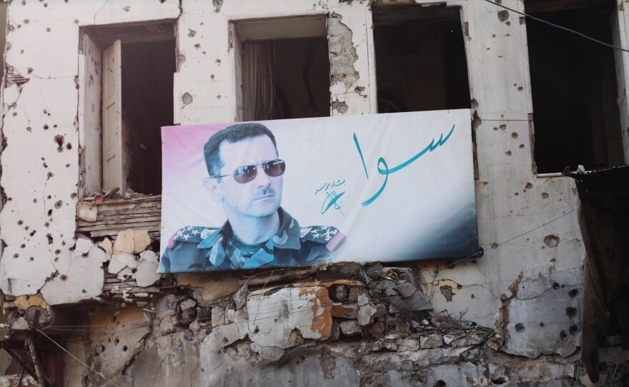 A portrait of President Bashar Assad hangs in Homs. The slogan reads "together."