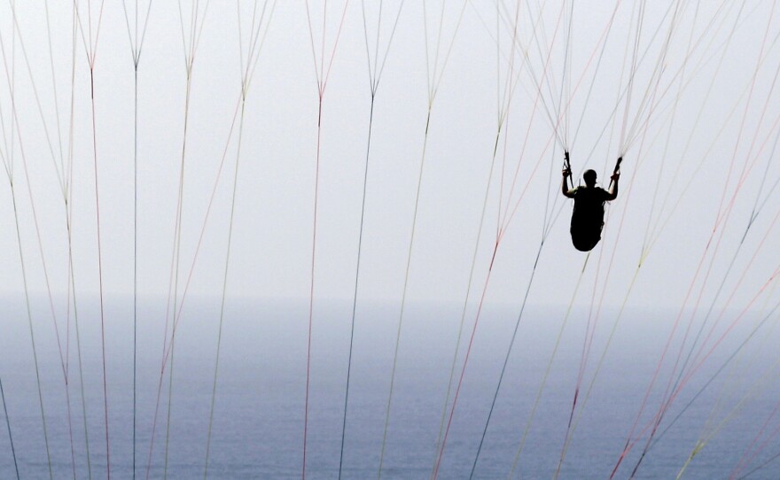 In this 2012 photo, a man paraglides behind the lines of another paraglider off the Torrey Pines Gliderport in San Diego.