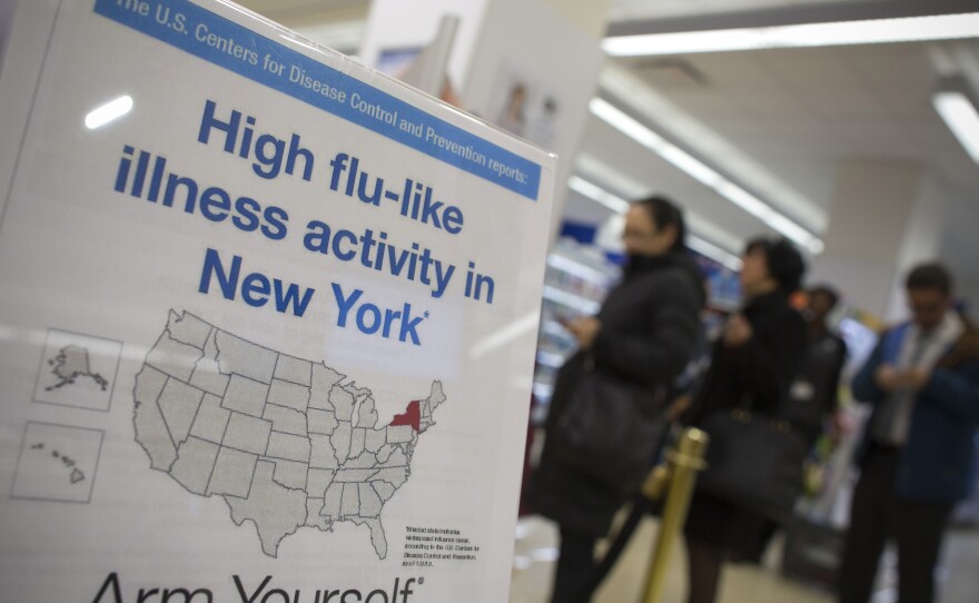 People line up at a Duane Reade pharmacy in New York behind a sign announcing the recent flu outbreak.