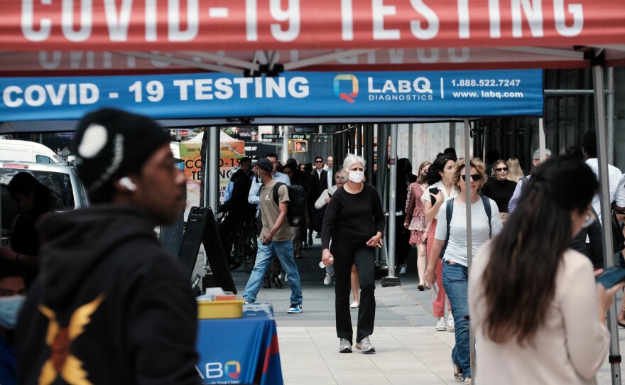 People walk past a Covid testing site on May 17. in New York City. New York's health commissioner, Dr. Ashwin Vasan, has moved from a "medium" COVID-19 alert level to a "high" alert level in all the five boroughs following a surge in cases.