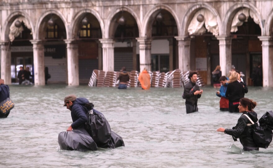 People walk in a flooded Saint Mark Square in Venice, Italy.