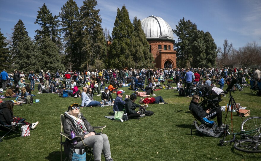 Eclipse watchers fill the lawn at Observatory Park, near the University of Denver, as the sun is partially blocked by the moon.