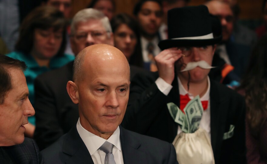 As former Equifax CEO Richard Smith prepares to testify before the Senate Banking Committee on Capitol Hill on Wednesday, activist Amanda Werner looks on through a monocle.