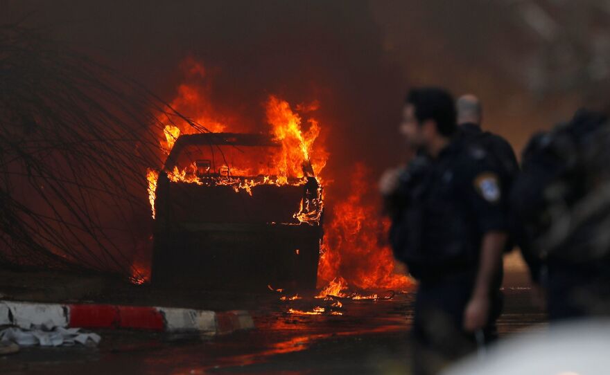 A vehicle burns outside a factory that was apparently hit with rocket fire Tuesday in the southern Israeli town of Sderot. Israel's military announced it had killed a commander of the Palestinian militant group Islamic Jihad in an early morning strike on his home in the Gaza Strip, prompting retaliatory barrages from Gaza.
