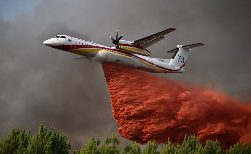 A plane releases fire retardant as it flies over a forest near Blagon, during wildfires in southwestern France, July 29, 2026.