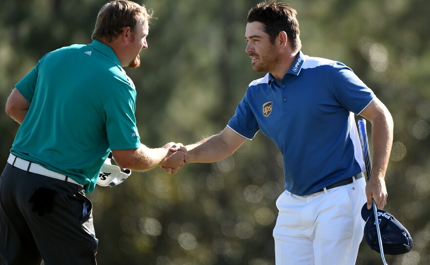 Louis Oosthuizen (right) shakes hands with his playing partner, J.B. Holmes, after the final round of the Masters on Sunday. Oosthuizen made an unlikely hole-in-one after his ball smacked Holmes' and then trickled into the cup.