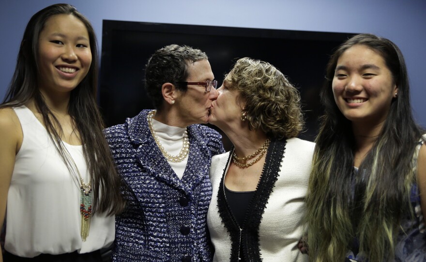 Sarah Goodfriend (left center) and Suzanne Bryant share a kiss Thursday as they pose with their daughters, Dawn Goodfriend (left) and Ting Goodfriend following a news conference in Austin.