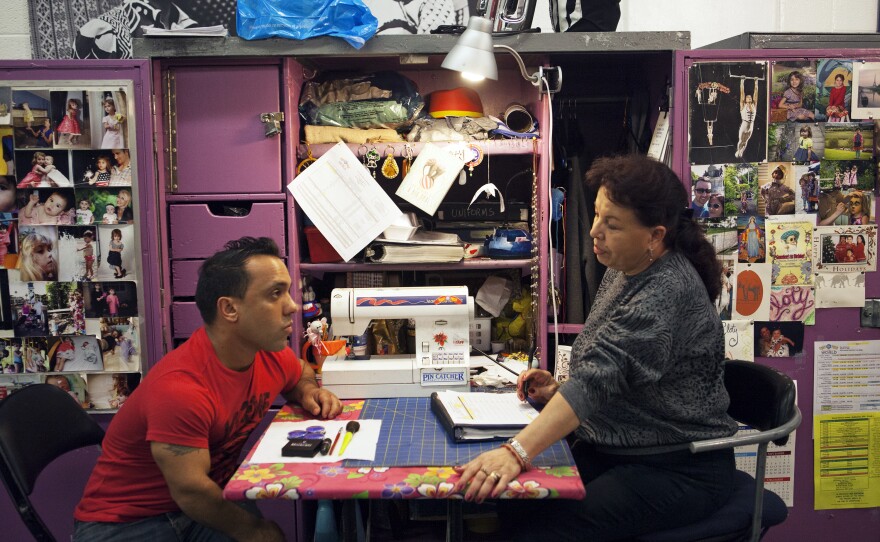 Performer Paulo dos Santos (left), who plays one of the central characters in "Out of this World," speaks with Cloty Gutierrez, the head of costume repair.