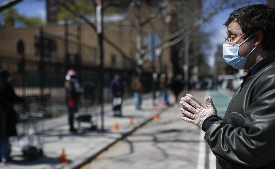 Christopher Love, general manager of the Covenant Mercy Mission, leads a prayer beside a line of visitors waiting for food donations at Manor Community Church on Saturday in New York. An additional 758 people died from the coronavirus over the past 24 hours, Gov. Andrew Cuomo said on Sunday.