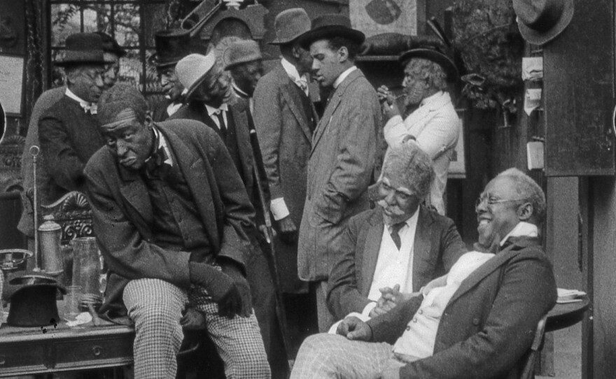 Scene still from <em>Bert Williams Lime Kiln Field Day Project.</em> Bert Williams, Walker Thompson (standing center), John Wesley Jenkins (seated right). In a concession to white audiences, Williams, the lead, wore blackface, but the other black characters did not.